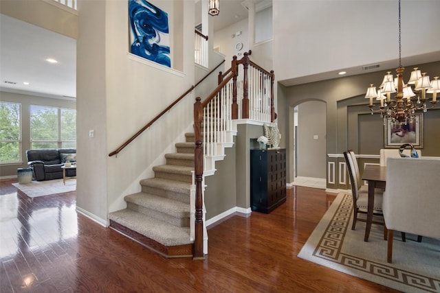 25 Falling Oaks Trl, The Hills, TX 78738 - stairway featuring arched walkways, wood finished floors, a high ceiling, a chandelier, and recessed lighting