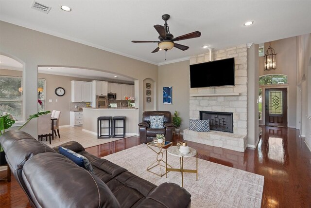 25 Falling Oaks Trl, The Hills, TX 78738 - living area with a ceiling fan, a fireplace, ornamental molding, arched walkways, and plenty of natural light