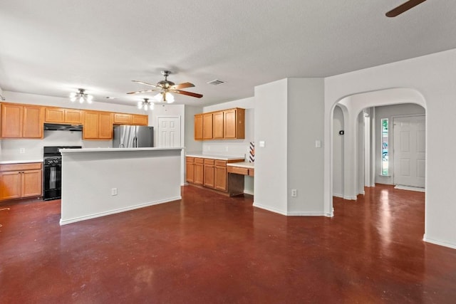 4608 Acers Ln, Austin, TX 78725 - kitchen with black gas stove, a ceiling fan, freestanding refrigerator, under cabinet range hood, and a textured ceiling