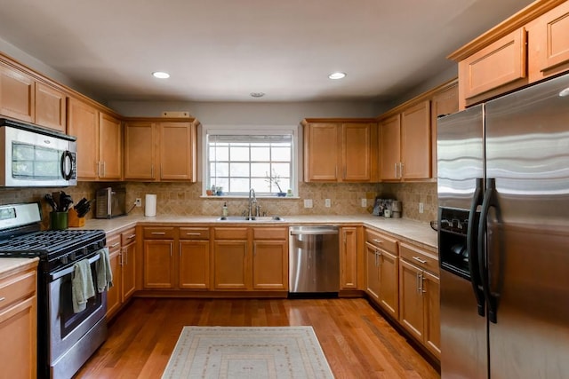6612 Ashland Dr, Austin, TX 78723 - kitchen featuring stainless steel appliances, light countertops, wood finished floors, decorative backsplash, and recessed lighting
