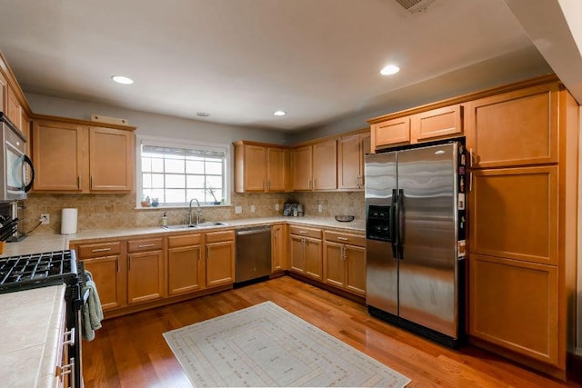 6612 Ashland Dr, Austin, TX 78723 - kitchen with appliances with stainless steel finishes, wood finished floors, tasteful backsplash, recessed lighting, and tile countertops
