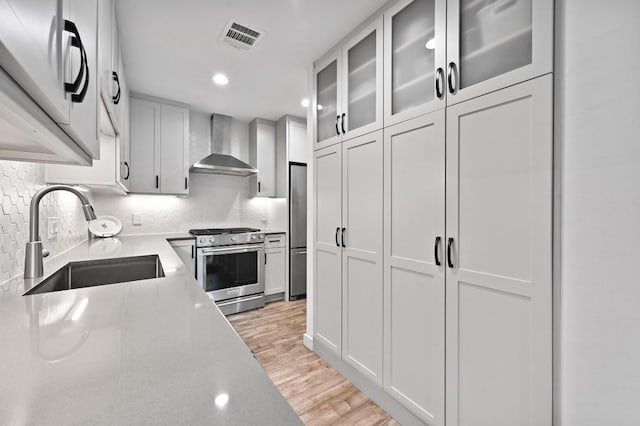 9710 Curlew Dr, Austin, TX 78748 - kitchen with wall chimney range hood, stainless steel appliances, light countertops, light wood finished floors, and tasteful backsplash