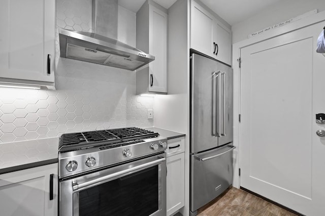 9710 Curlew Dr, Austin, TX 78748 - kitchen with stainless steel appliances, wall chimney exhaust hood, decorative backsplash, wood finished floors, and white cabinets