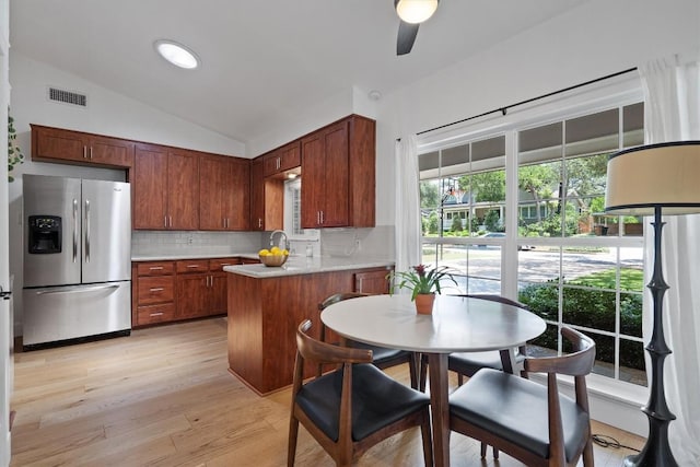 4604 Rue St, Austin, TX 78731 - kitchen featuring stainless steel fridge with ice dispenser, lofted ceiling, decorative backsplash, a peninsula, and light countertops