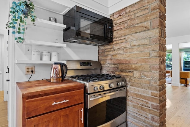 4604 Rue St, Austin, TX 78731 - kitchen with stainless steel range with gas stovetop, black microwave, open shelves, light wood-style flooring, and wooden counters