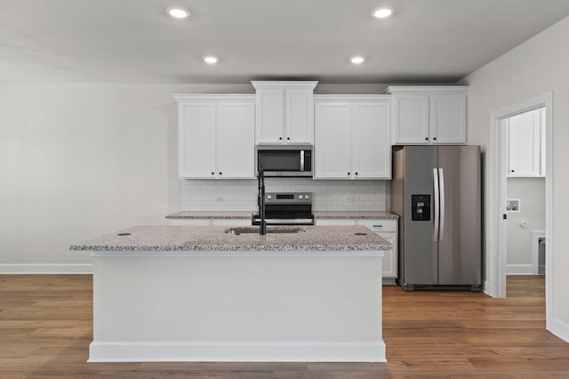 9517 Balmy Ln, Manor, TX 78653 - kitchen with appliances with stainless steel finishes, a kitchen island with sink, white cabinets, decorative backsplash, and recessed lighting