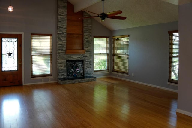 22631 John Rolfe Ln, Katy, TX 77449 - unfurnished living room featuring a ceiling fan, wood finished floors, a stone fireplace, beamed ceiling, and high vaulted ceiling