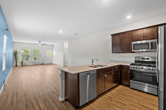 2416 Nightview Dr, Pflugerville, TX 78660 - kitchen with appliances with stainless steel finishes, light wood-style floors, open floor plan, a peninsula, and dark brown cabinetry