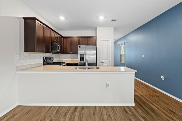 2416 Nightview Dr, Pflugerville, TX 78660 - kitchen with stainless steel appliances, dark brown cabinetry, wood finished floors, light countertops, and backsplash