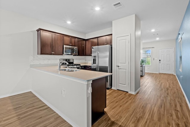 2416 Nightview Dr, Pflugerville, TX 78660 - kitchen with appliances with stainless steel finishes, light wood-style floors, backsplash, dark brown cabinets, and recessed lighting