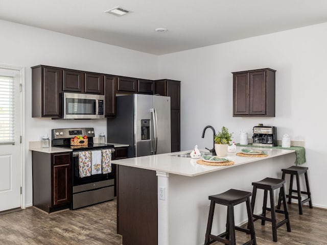 752 Circle Way Unit 35H, Jarrell, TX 76537 - kitchen featuring appliances with stainless steel finishes, dark wood-style flooring, dark brown cabinetry, a breakfast bar, and light countertops
