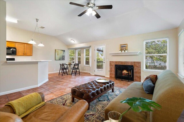 1601 Muledeer Run, Leander, TX 78641 - living room featuring light tile patterned flooring, vaulted ceiling, healthy amount of natural light, a ceiling fan, and a fireplace