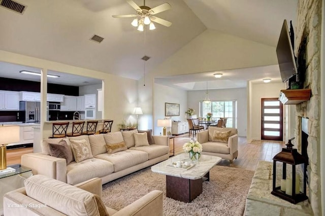 128 Moku Manu Dr, Bastrop, TX 78602 - living area with a ceiling fan, light wood finished floors, high vaulted ceiling, and a stone fireplace
