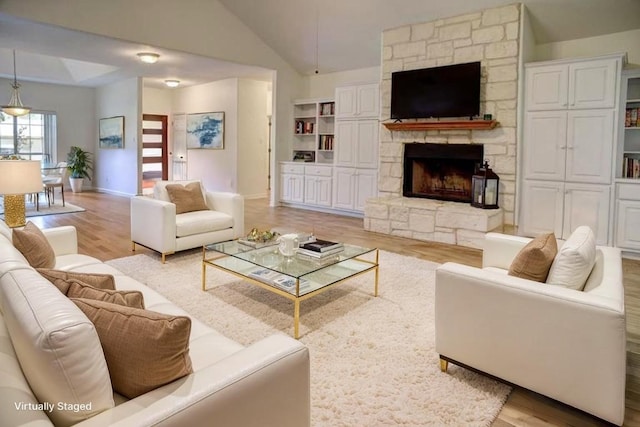 128 Moku Manu Dr, Bastrop, TX 78602 - living area with light wood-style flooring, vaulted ceiling, and a stone fireplace