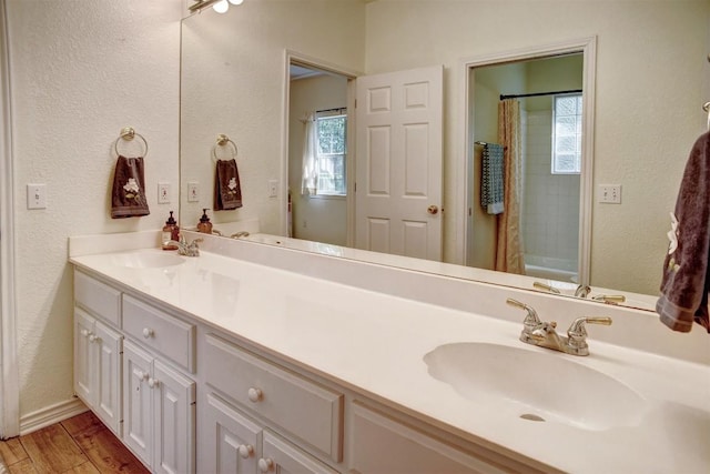 128 Moku Manu Dr, Bastrop, TX 78602 - bathroom featuring double vanity, a textured wall, wood finished floors, and shower / bath combination with curtain