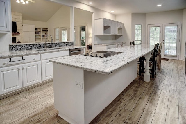 128 Moku Manu Dr, Bastrop, TX 78602 - kitchen featuring black electric stovetop, light wood-style flooring, light stone countertops, white cabinetry, and recessed lighting