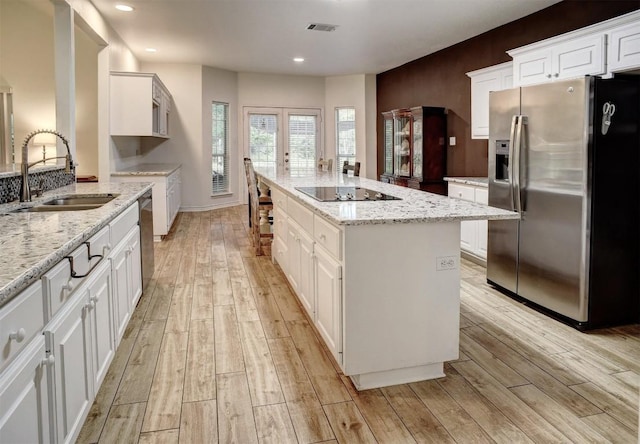 128 Moku Manu Dr, Bastrop, TX 78602 - kitchen featuring stainless steel appliances, light wood-style floors, white cabinets, a kitchen island, and recessed lighting