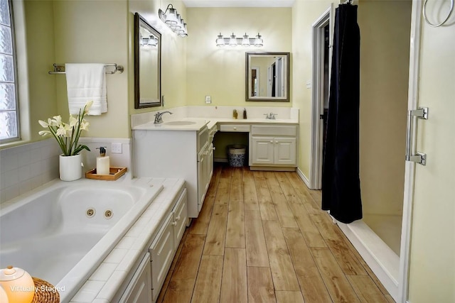 128 Moku Manu Dr, Bastrop, TX 78602 - bathroom with double vanity, wood finished floors, and a jetted tub