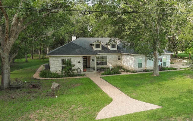 128 Moku Manu Dr, Bastrop, TX 78602 - new england style home featuring a chimney, a front lawn, stone siding, and a shingled roof