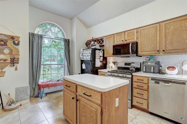 5907 Shanghai Pierce Rd, Austin, TX 78749 - kitchen with appliances with stainless steel finishes, vaulted ceiling, tasteful backsplash, light tile patterned flooring, and light countertops