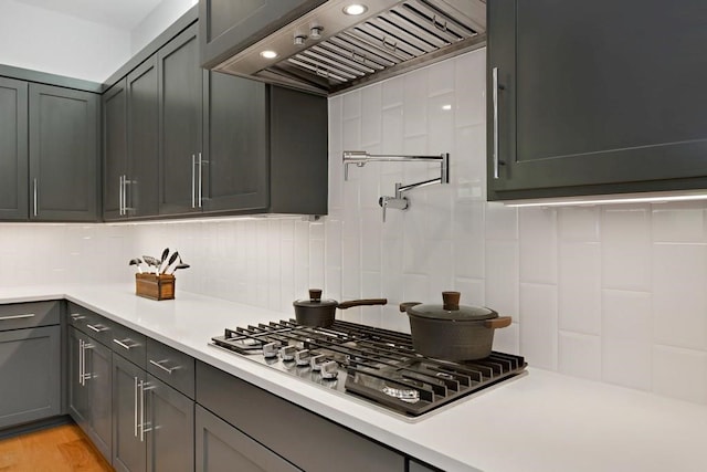 1719 Bunche Rd, Austin, TX 78721 - kitchen with stainless steel gas cooktop, custom range hood, tasteful backsplash, and light countertops