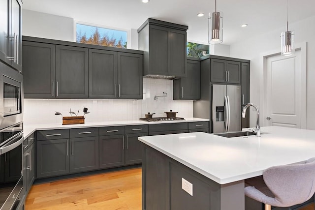 1719 Bunche Rd, Austin, TX 78721 - kitchen with appliances with stainless steel finishes, light wood-type flooring, tasteful backsplash, light countertops, and pendant lighting