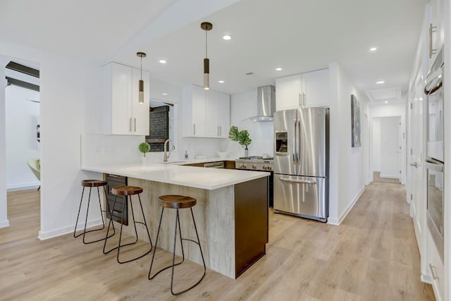 10206 Cripple Creek Cv, Austin, TX 78758 - kitchen with appliances with stainless steel finishes, wall chimney exhaust hood, a peninsula, a kitchen breakfast bar, and white cabinets