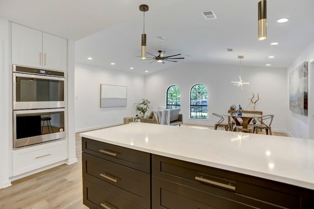 10206 Cripple Creek Cv, Austin, TX 78758 - kitchen with stainless steel double oven, light countertops, hanging light fixtures, light wood-style floors, and a ceiling fan