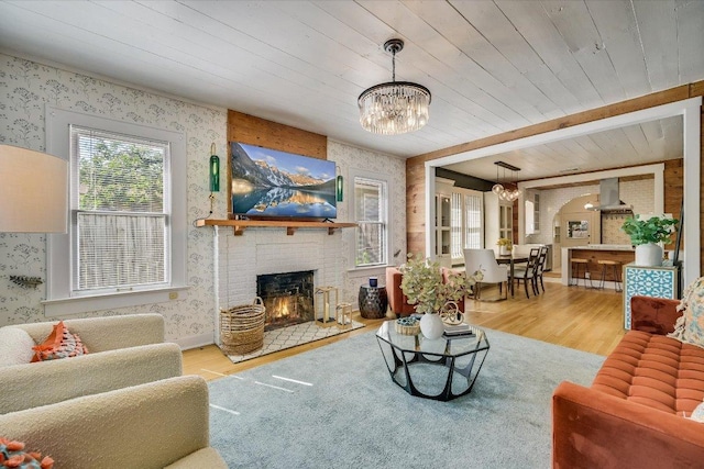 510 E 38th St, Austin, TX 78705 - living room with wallpapered walls, a chandelier, wood finished floors, a fireplace, and a wood ceiling with exposed beams