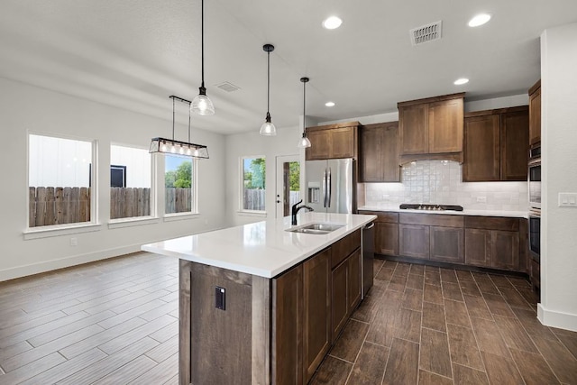 182 W Torrey St, New Braunfels, TX 78130 - kitchen featuring stainless steel appliances, wood tiled floors, light countertops, tasteful backsplash, and a kitchen island with sink