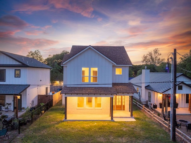182 W Torrey St, New Braunfels, TX 78130 - back of property at dusk with a shingled roof, a patio, board and batten siding, and a fenced backyard