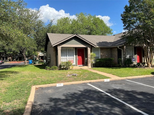 1015 E Yager Ln Unit 77, Austin, TX 78753 - view of front of house featuring uncovered parking, a front lawn, brick siding, and a shingled roof
