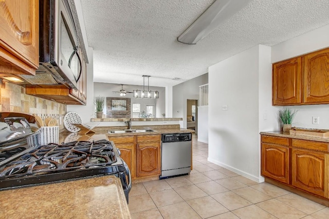 17516 Klamath Falls Dr, Round Rock, TX 78681 - kitchen featuring stainless steel appliances, brown cabinetry, a textured ceiling, a peninsula, and light tile patterned floors