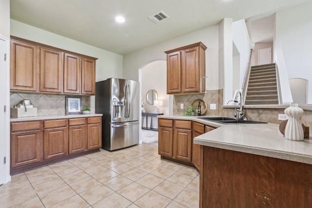 212 Boone Valley Dr, Round Rock, TX 78664 - kitchen featuring stainless steel refrigerator with ice dispenser, brown cabinets, light countertops, backsplash, and recessed lighting