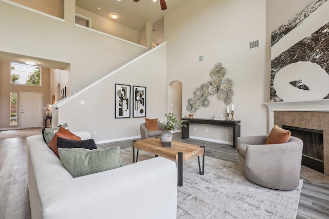 212 Boone Valley Dr, Round Rock, TX 78664 - living area featuring a high ceiling, stairway, wood finished floors, arched walkways, and a tiled fireplace