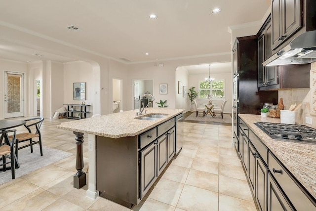 1200 Falling Hills Dr, Georgetown, TX 78628 - kitchen featuring arched walkways, under cabinet range hood, appliances with stainless steel finishes, a center island with sink, and recessed lighting