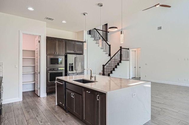 520 Germander Rd, Leander, TX 78641 - kitchen with appliances with stainless steel finishes, light wood-style floors, dark brown cabinets, light stone countertops, and hanging light fixtures
