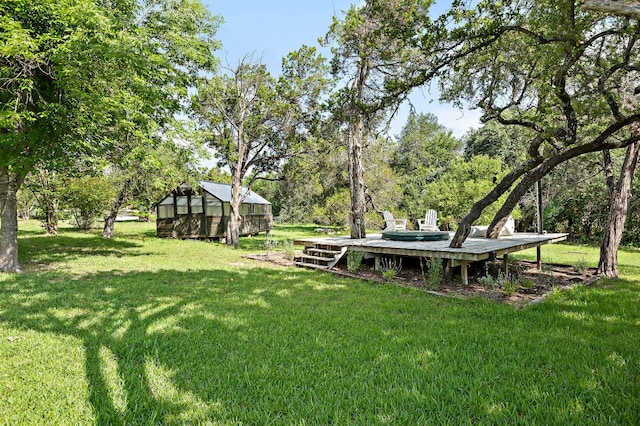 5204 Cueva Dr, Austin, TX 78738 - view of grassy yard with a greenhouse, an outbuilding, view of wooded area, and a wooden deck
