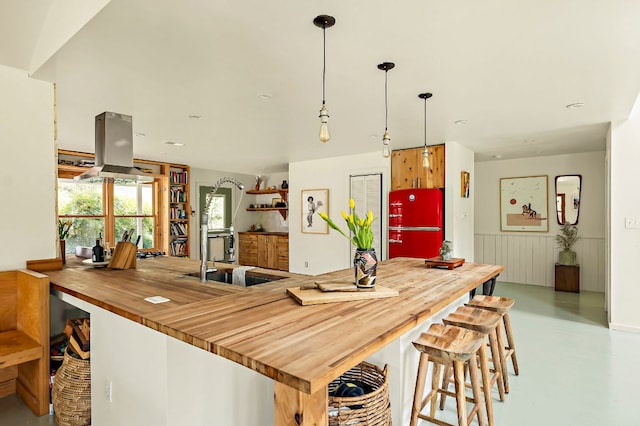5204 Cueva Dr, Austin, TX 78738 - kitchen with butcher block counters, island exhaust hood, freestanding refrigerator, concrete flooring, and decorative light fixtures