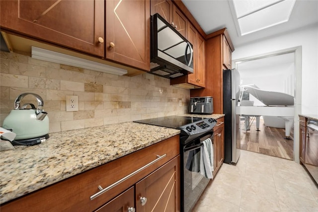 7162 Chimney Cors Unit 7204, Austin, TX 78731 - kitchen featuring appliances with stainless steel finishes, light stone counters, tasteful backsplash, brown cabinetry, and light tile patterned floors