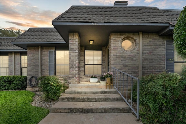 7162 Chimney Cors Unit 7204, Austin, TX 78731 - view of exterior entry with a shingled roof and brick siding