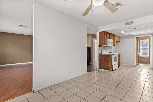 1703 Greyson Dr, Round Rock, TX 78664 - kitchen with white appliances, light tile patterned floors, ceiling fan, light countertops, and brown cabinets