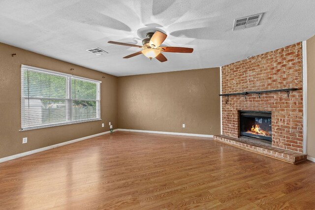 1703 Greyson Dr, Round Rock, TX 78664 - unfurnished living room featuring ceiling fan, wood finished floors, a fireplace, and a textured ceiling