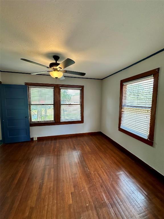 121 Wyers Pl, Cedar Creek, TX 78612 - empty room with dark wood finished floors, plenty of natural light, and ceiling fan