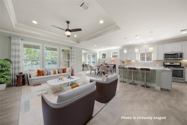 14 Acacia Way, Georgetown, TX 78633 - living area featuring plenty of natural light, a tray ceiling, a ceiling fan, recessed lighting, and crown molding