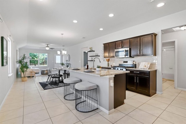 2010 Grow Ln, Austin, TX 78754 - kitchen with stainless steel microwave, decorative backsplash, light stone counters, recessed lighting, and light tile patterned flooring