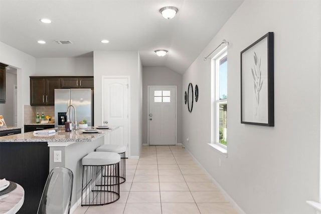 2010 Grow Ln, Austin, TX 78754 - kitchen featuring stainless steel fridge with ice dispenser, a kitchen bar, dark brown cabinets, light tile patterned floors, and backsplash