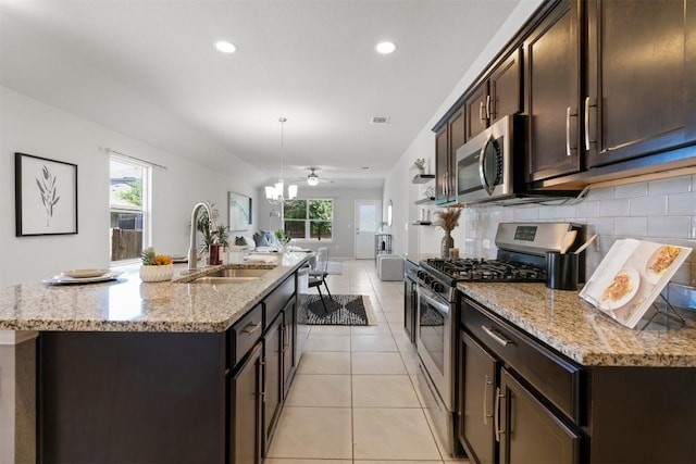 2010 Grow Ln, Austin, TX 78754 - kitchen with stainless steel appliances, dark brown cabinets, a kitchen island with sink, a ceiling fan, and recessed lighting