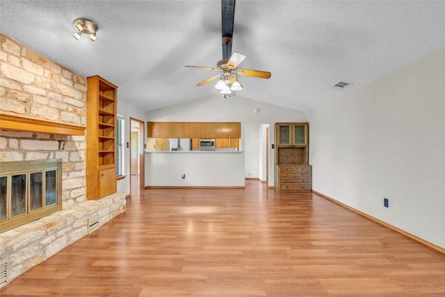 209 Lenz St, Round Rock, TX 78681 - unfurnished living room with a ceiling fan, light wood finished floors, a textured ceiling, and a stone fireplace