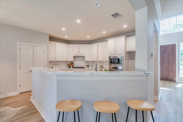 2804 Forest Green Dr, Round Rock, TX 78665 - kitchen with light wood-type flooring, appliances with stainless steel finishes, tasteful backsplash, white cabinets, and healthy amount of natural light